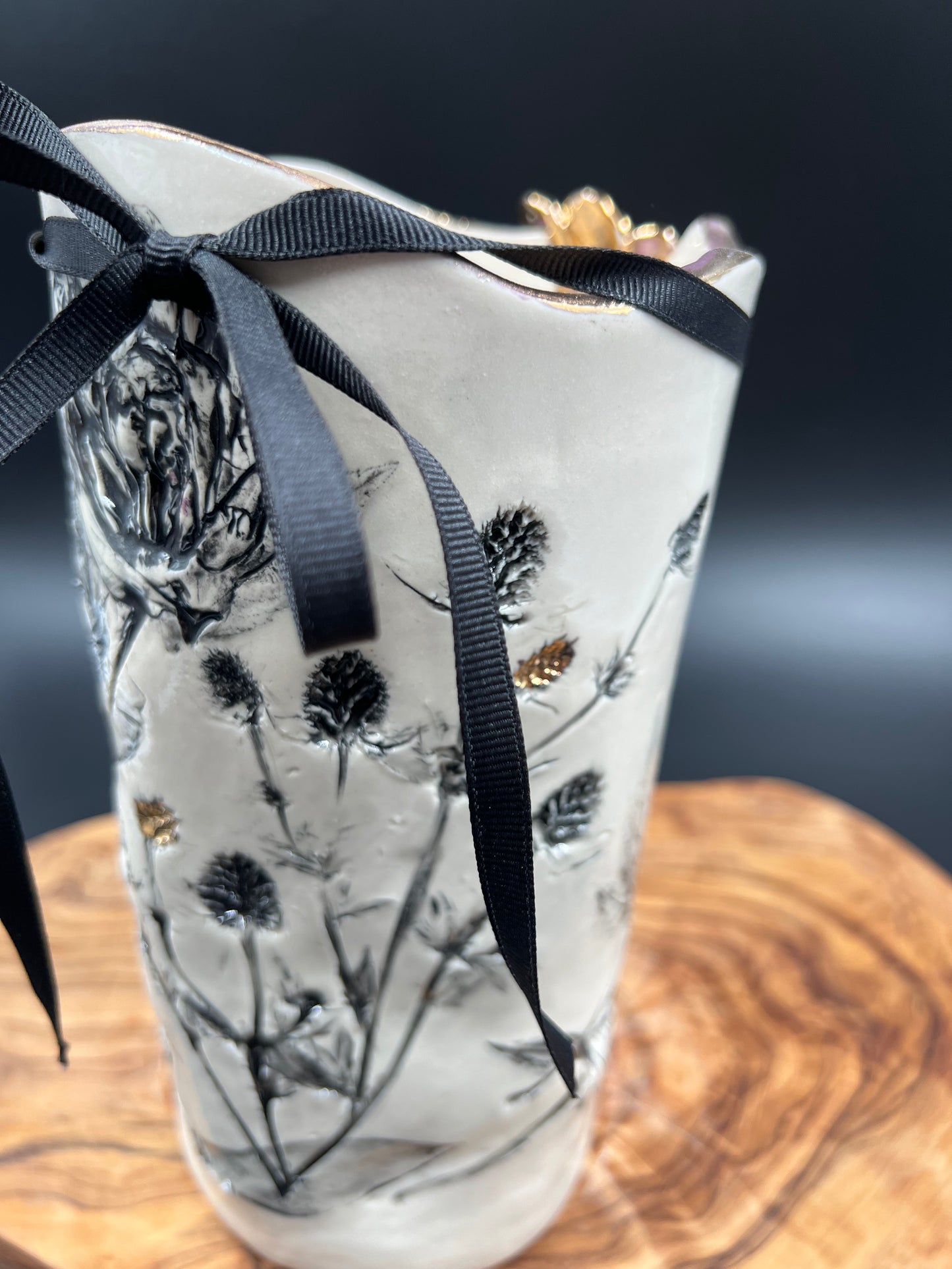 Black floral vase with gold flower at lip, gold rim