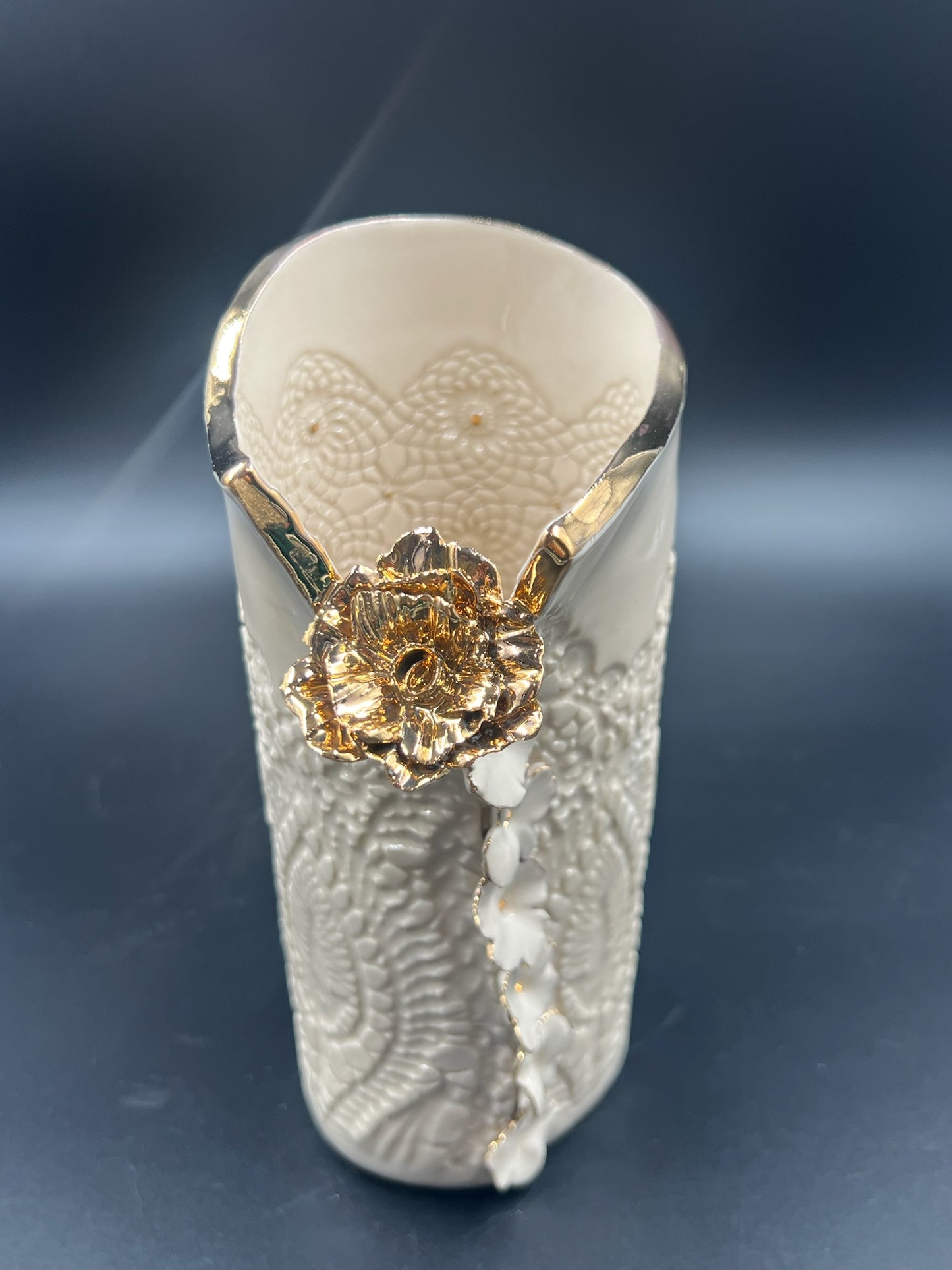 Cream lace vase with flower at lip, gold rim, cascading flowers