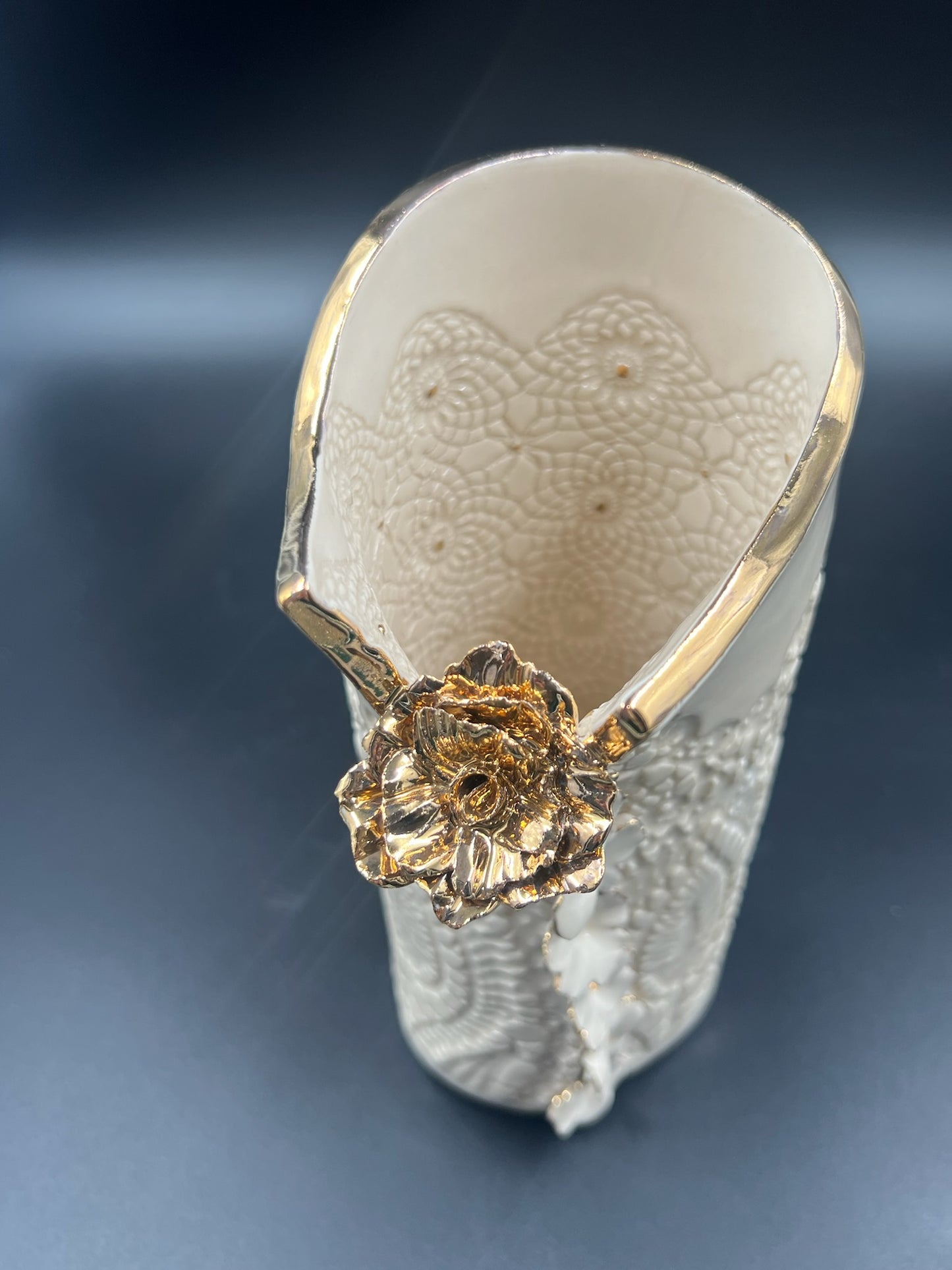 Cream lace vase with flower at lip, gold rim, cascading flowers