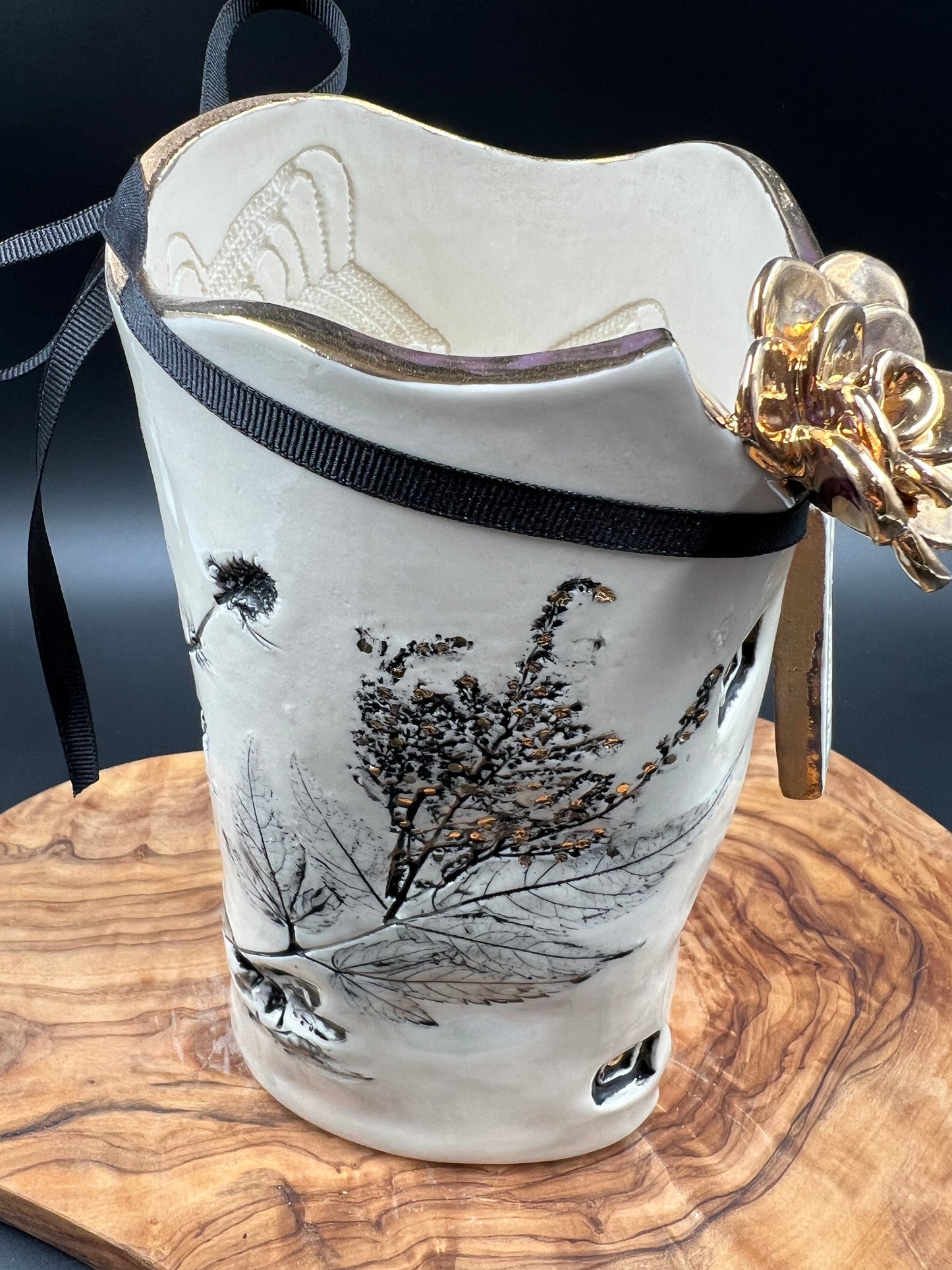 Black floral vase with gold flower at lip, gold rim