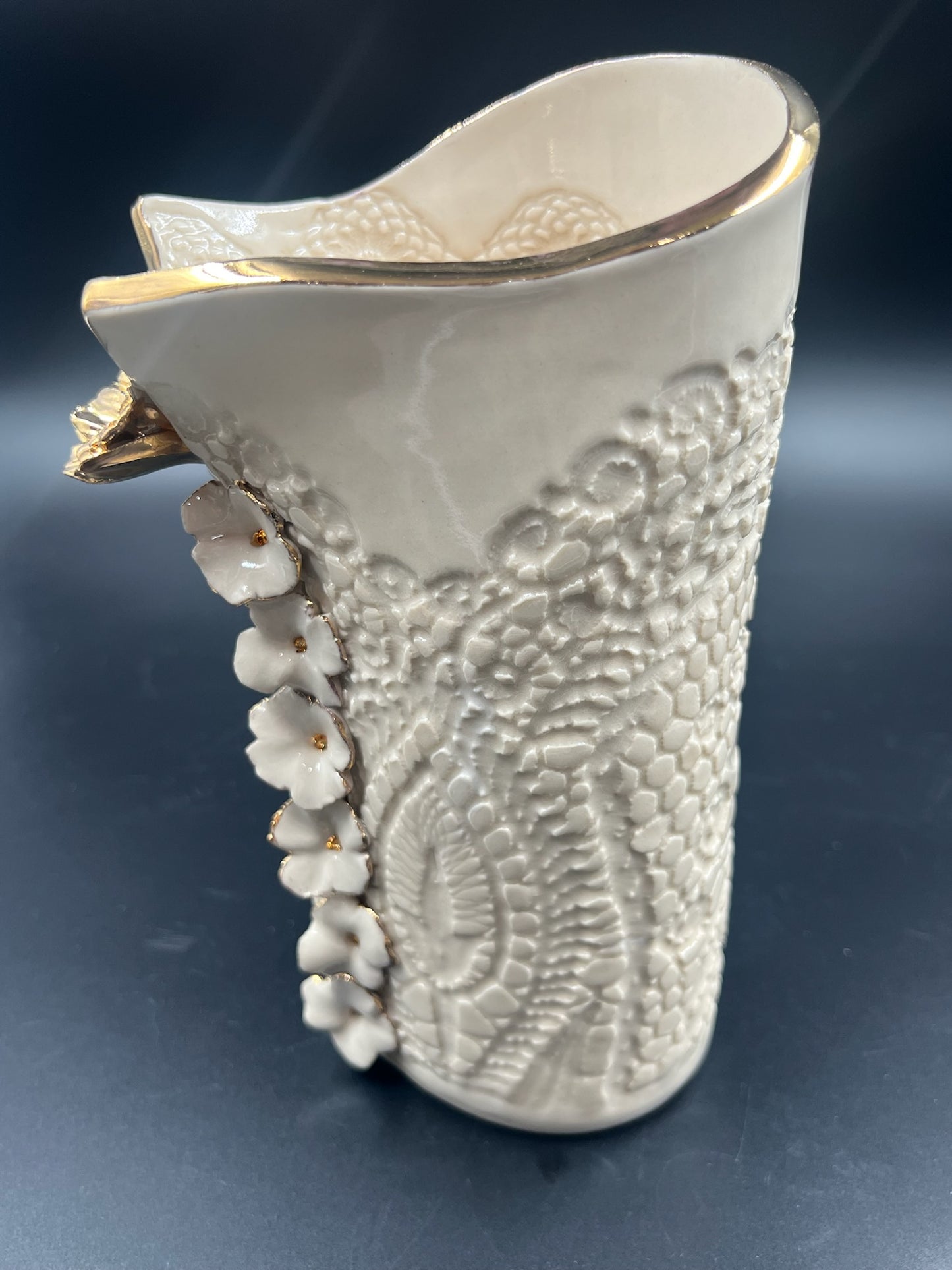 Cream lace vase with flower at lip, gold rim, cascading flowers